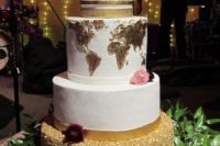 a chic wedding cake with a gold glitter tier, two white ones and a gold world map tier plus a calligraphy topper