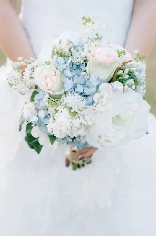 a delicate wedding bouquet featuring blue hydrangeas, light pink roses, lush white peonies is a beautiful idea for a summer wedding