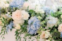 a delicate wedding centerpiece of pink, white and blue hydrangeas and greenery, thistles and other beautiful stuff is a great idea