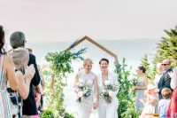 a geometric wedding arch decorated with greenery, blue and white blooms and with cool views for a summer ski resort wedding