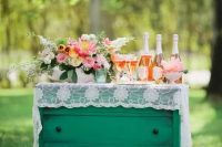a green vintage dresser covered with white lace, with bold blooms and greenery and candles in green candle holders is a lovely idea