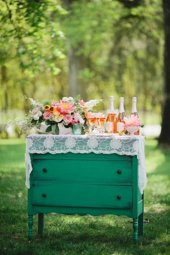 a green vintage dresser covered with white lace, with bold blooms and greenery and candles in green candle holders is a lovely idea