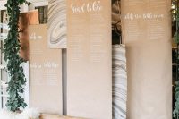 a lovely wedding seating chart of kraft paper with white calligraphy and some marble pieces is a lovely and chic idea
