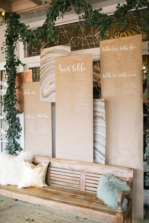 a lovely wedding seating chart of kraft paper with white calligraphy and some marble pieces is a lovely and chic idea