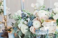 a pastel wedding tablescape with a serenity blue table and glasses, blue candles, pastel and white blooms and blue thistles