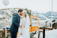a rustic wedding arch of birch wood, greenery and neutral blooms with lovely views of the moutains is cool