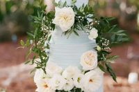 a serenity blue textural buttercream wedding cake decorated with white blooms and greenery for a spring or summer wedding
