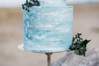 a serenity blue watercolor wedding cake with silver leaf and privet berries is a nice idea for a beach wedding