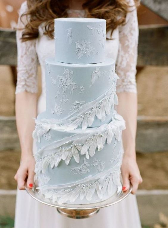 a serenity blue wedding cake decorated with white brushstrokes, feathers and beads for a truly boho wedding