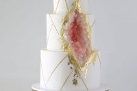 a sophisticated white wedding cake with gold touches and rose quartz plus gold leaf around it looks very chic