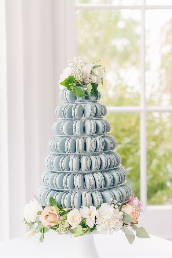 a tower of serenity blue macarons topped with blush and white blooms is a lovely alternative to a usual wedding cake