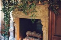 a vintage refined fireplace with dark candles, firewood and lush foliage on the mantel