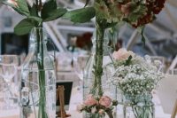 a wedding reception table decorated with newspapers , with bottles with various fresh blooms is a gorgeous idea