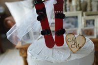 a white textural wedding cake with burlap and lace, a wood heart and red snowboards on top for a cute touch