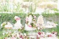 a white vintage dresser decorated with blush and mauve blooms, greenery and with lots of desserts, sweets and wedding cakes is wow