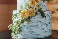 aserenity blue tiered ruffle wedding cake with yellow to orange blooms and greeneryfor a summer wedding