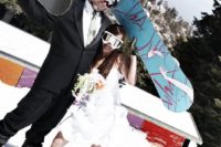 fun wedding portraits of the couple showing off their snowboards right in the snow on the mountains