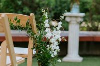 green wine bottles with greenery and white blooms are a great idea to line up the aisle at a rustic or other relaxed and not too formal wedding
