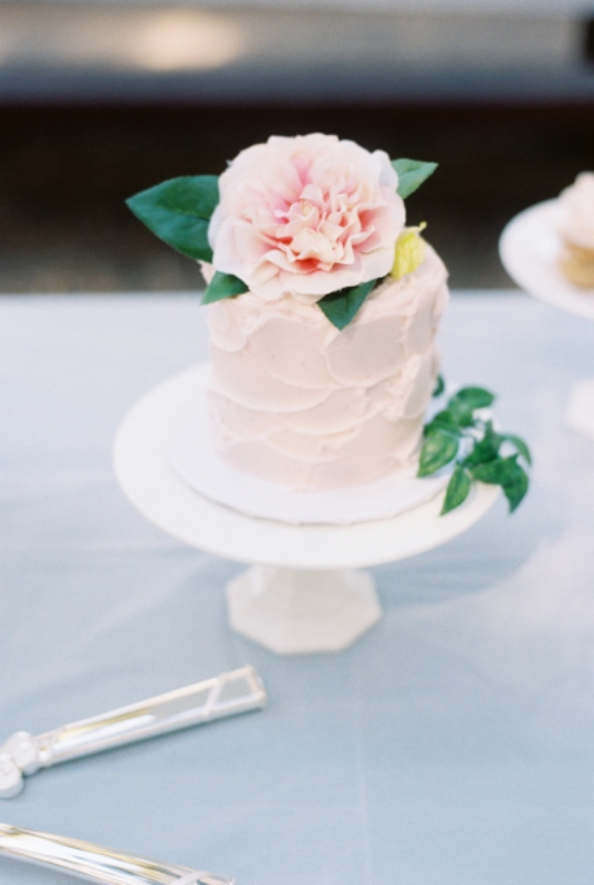 a textural rose quartz mini wedding cake topped with a matching large blooms and leaves