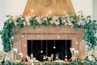 pastel blooms, greenery, floating candles and crystals hanging down from the mantel for a delicate and chic look