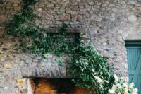 pillar candles in the fireplace, greenery and pampas grass climbing up the stone wall for a refined and cozy feel