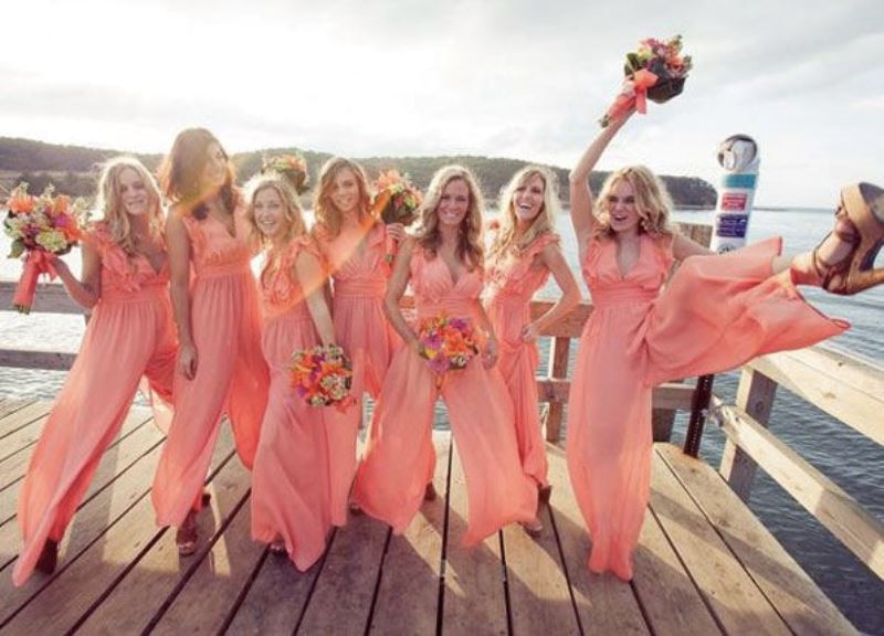 Sleveless coral pink bridesmaid jumpsuits with a ruffled bodice and wideleg pants for a summer wedding