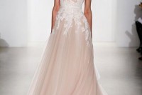 a blush A-line wedding dress with thick straps, a deep cut and draping looks very refined and very romantic