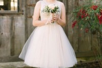 an A-line knee sleeveless wedding dress with an illusion neckline and a full skirt for a ballerina-like look