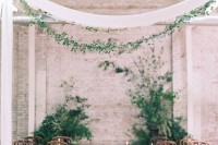 a romantic botanical wedding ceremony space with lush greenery, candles, greenery garlands and neutral textiles over the space
