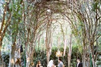 a lush botanical space with greenery walls, bushes, tree arches with lights for a refined wedding ceremony