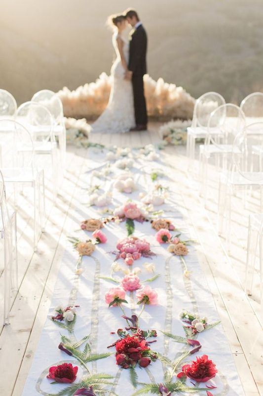 a botanical wedding ceremony space with a pampas grass altar, ombre blooms lining up the aisle