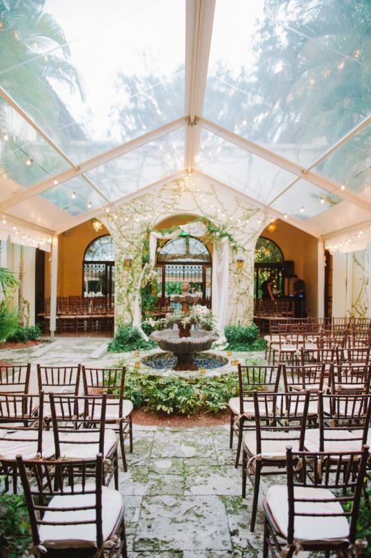 a refined and chic botanical wedding space with a fountain decorated with greenery and leaves, greenery on the floor and on the walls