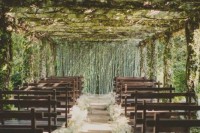 a lush botanical wedding ceremony space with greenery all over the space and baby’s breath lining up the aisle