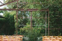 an old greenhouse with greenery around for a backdrop, greenery and pomegranates lining up the aisle