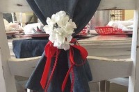 a denim table runner with white blooms and a red ribbon bow for accenting a table