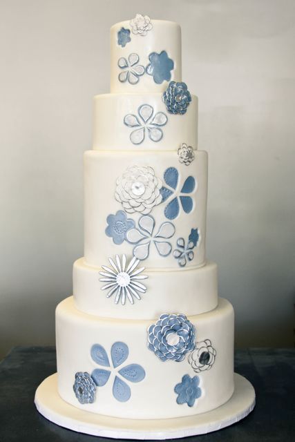 a white wedding cake with blue floral and other decor that reminds of traditional denim colors