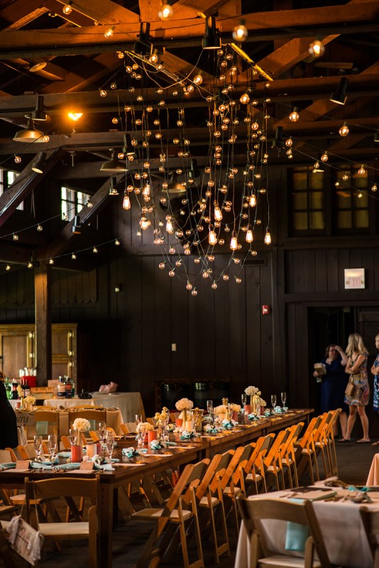 a barn wedding reception with neutral blooms, candles and bulbs hanging over the table is a lovely idea to rock