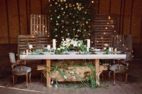 a reception space decorated with wooden screens with lights, greenery and neutral blooms, greenery runners and a decoration under the table