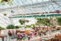 a bold and chic wedding reception space with potted greenery, hanging arrangements and kokedama, bright florals on the table