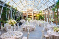 an elegant and refined wedding venue with greenery climbing up the walls, neutral and pastel blooms for centerpieces