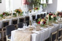 a beautiful wedding reception space with bright blooms and greenery on the table and kokedama balls hanging over the space and a greenery arrangement in the corner