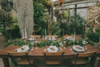 a botanical wedding reception space with lots of gorwing bushes and plants, grasses and hanging plants, greenery runners to match the space