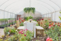 a bright wedding reception space with greenery and bright blooms in plants, a greenery chandelier and a centerpiece to make the reception very lively and fresh