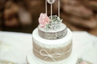 a rustic wedding cake with white textural buttercream, burlap, twine and pink roses and baby’s breath plus wood slice cake toppers