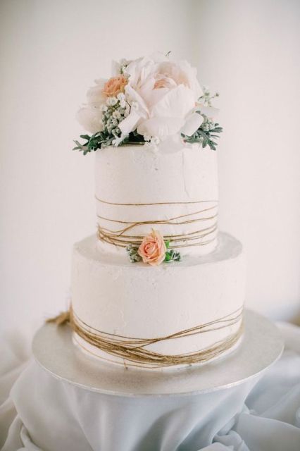 a white textural wedding cake wrapped with twine, blush and white blooms and greenery is a beautiful idea for a rustic wedding