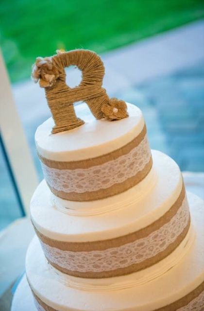 a rustic wedding cake wrapped with burlap and lace, with a twine wrapped monogram on top is a chic idea for a rustic wedding
