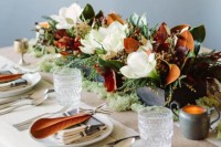 a creative wedding centerpiece of a box and some greenery and magnolia leaves and blooms is a chic decor idea