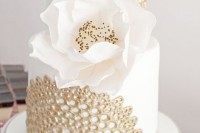 a white and gold lace wedding cake topped with a single large magnolia bloom for an ultimate elegant and chic look