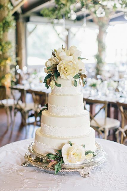 a white lace wedding cake with magnolia leaves and blooms is a cool idea to make a statement at the wedding