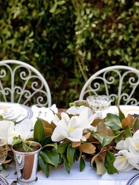 a magnolia leaf and bloom table runner is a very fresh and bold idea to decorate the table